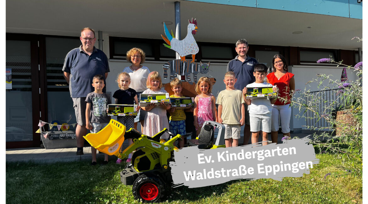 Kinder und Erwachsene vor dem Evangelischen Kindergarten Waldstraße in Eppingen mit Spielzeug-Baufahrzeugen und einem großen Traktor mit gelber Schaufel.